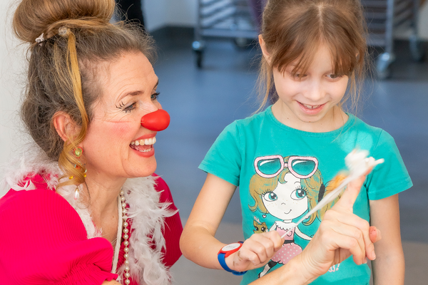 Eine Clownin der ROTE NASEN und ein Mädchen bei einer Interaktion.