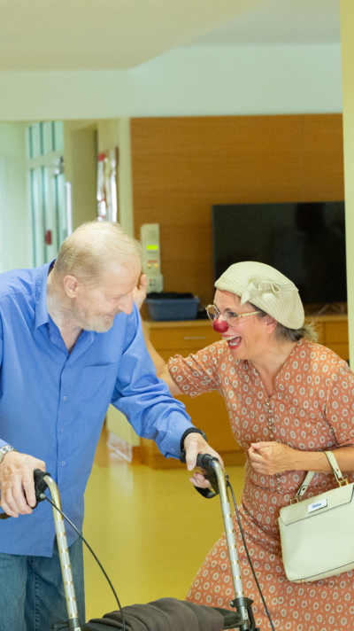 Clownin Herta begleitet einen älteren Herren.