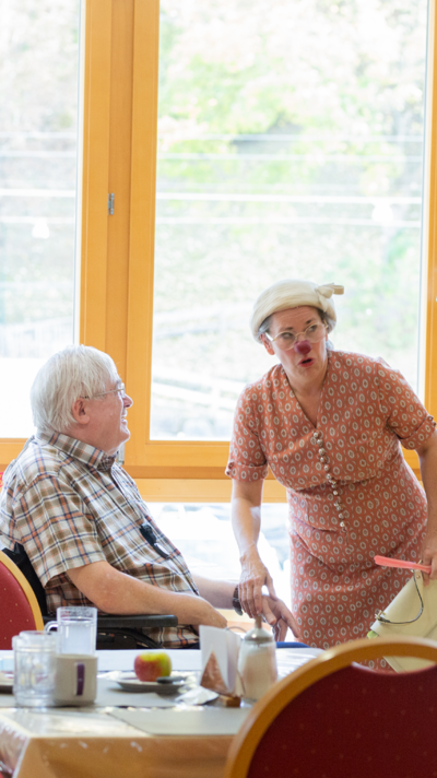 Ein älterer Herr und Clownin Herta führen ein Gespräch.