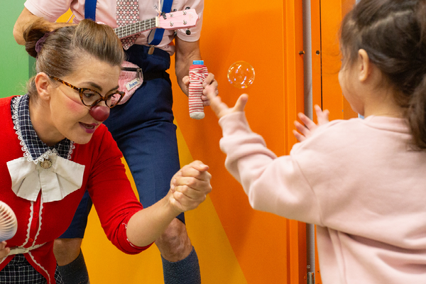 Die kleine Helena, Clownin Hildegard und Clown Anton spielen mit Seifenblasen.