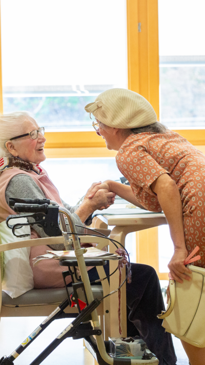 Clownin Herta reicht einer Heimbewohnerin die Hand.