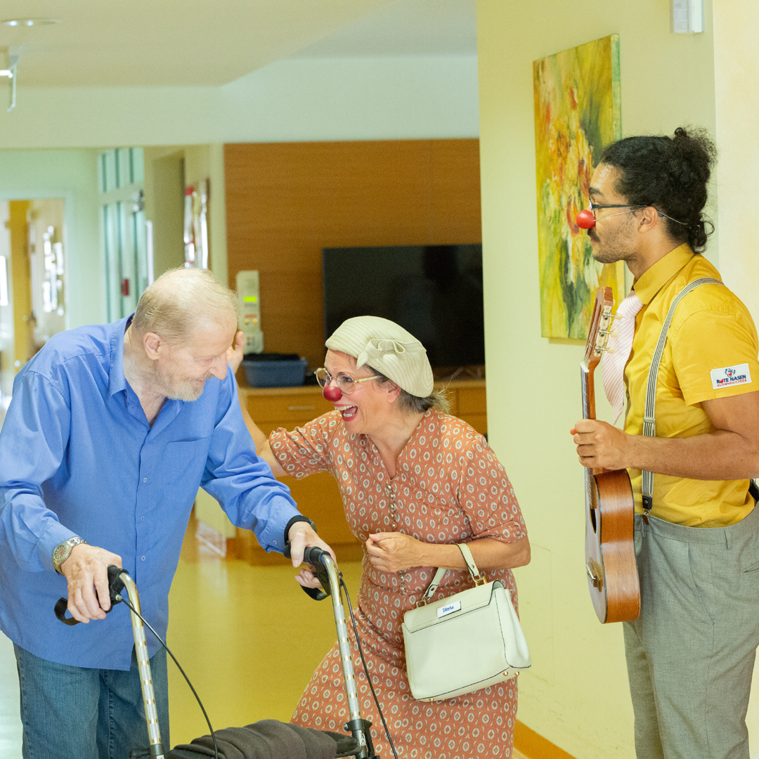 Clownin Herta und Clown Ferdinand begleiten einen älteren Herren.