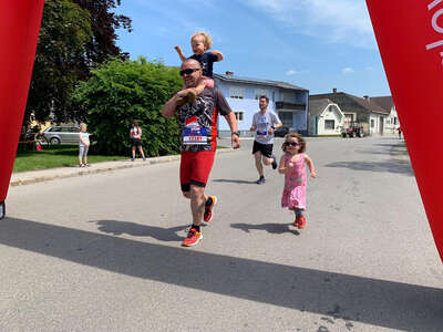 Zieleinlauf eines Papas mit zwei Kindern beim ROTE NASEN LAUF Reisenberg