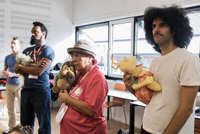 Drei Männer halten Handpuppen in der Hand